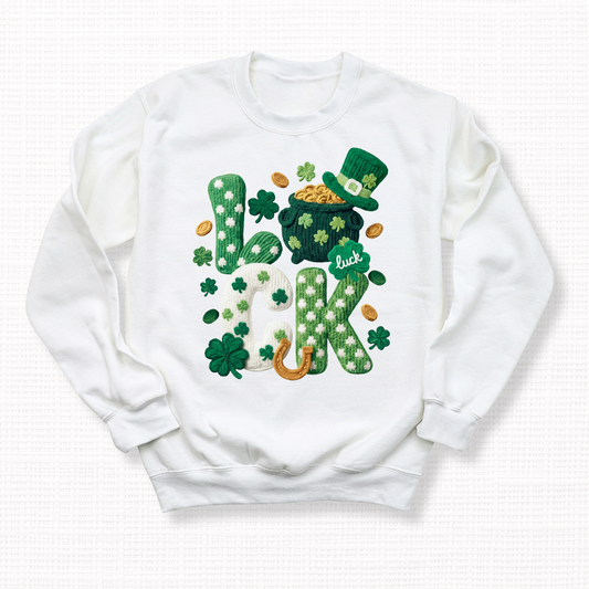 St. Patrick’s Day t-shirt with textured “Lucky” shamrock lettering, pot of gold, leprechaun hat, and horseshoe on a white crewneck sweatshirt.