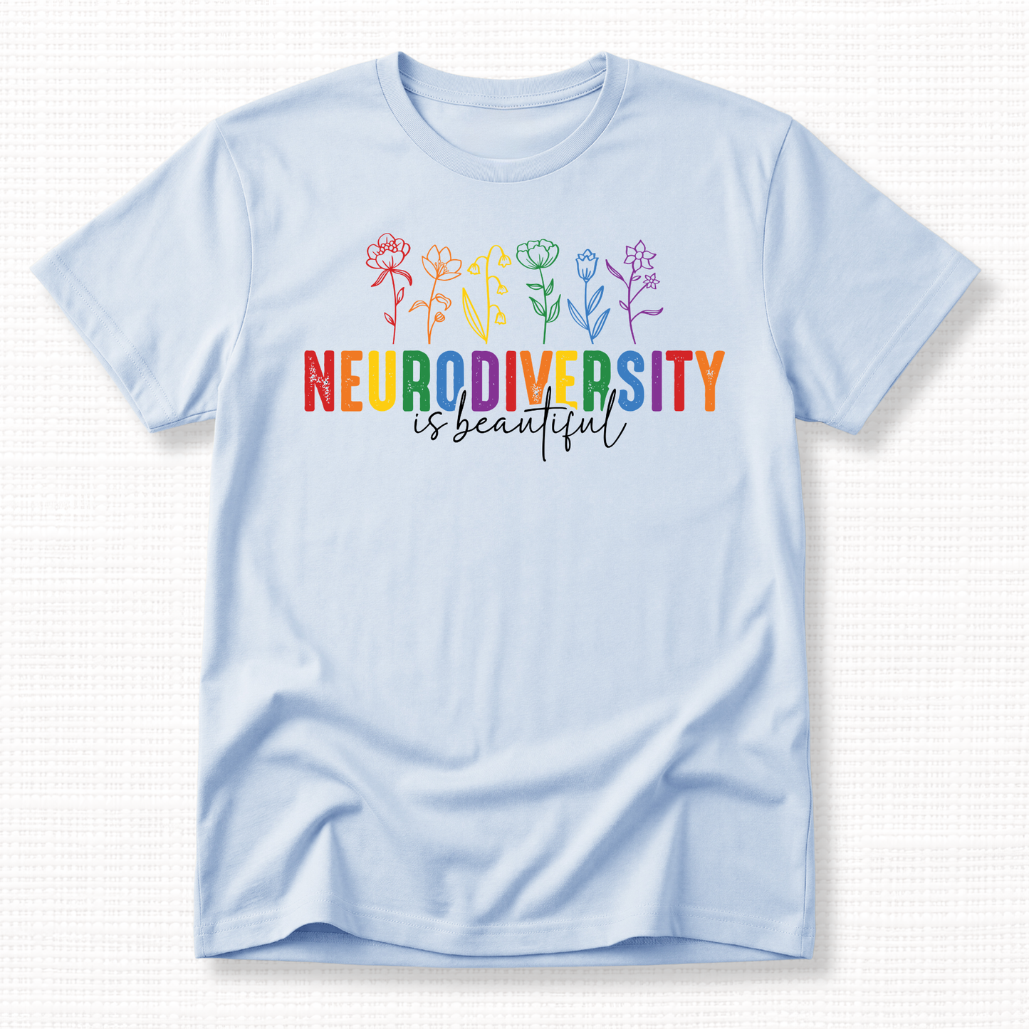 Light blue t-shirt with rainbow 'Neurodiversity is beautiful' text and colorful flowers.