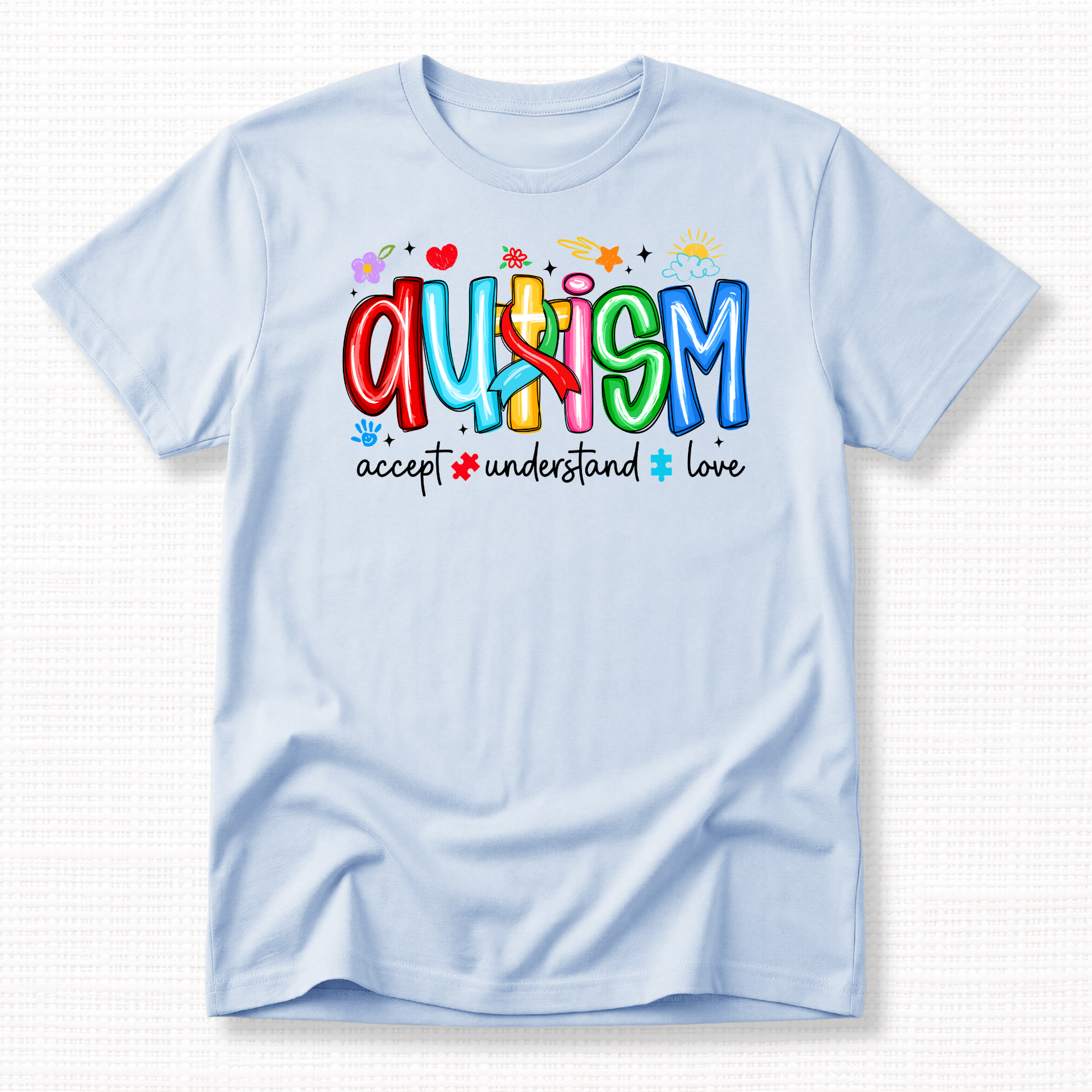 A light blue shirt with colorful 'Autism' text and words 'Accept, Understand, Love' underneath in black.