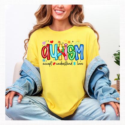 Person wearing a yellow shirt with colorful 'Autism' text and words 'Accept, Understand, Love' underneath in black.
