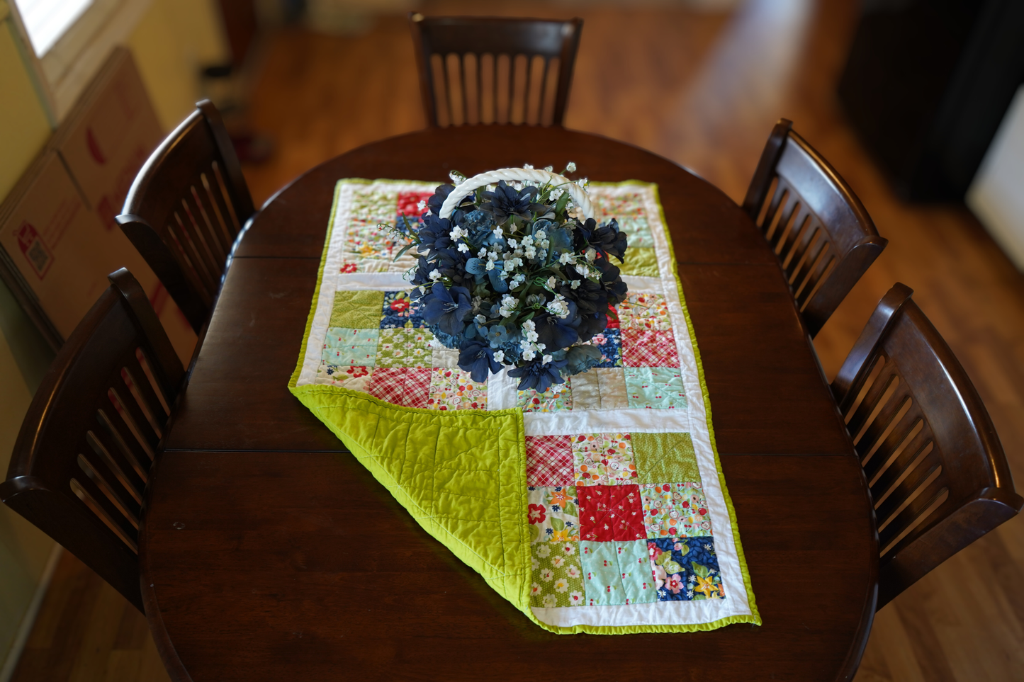 April Rosenthal orchard fabric quilted table runner fruit print patchwork 25x39 handmade with apple green backing, displayed on a dining room table.