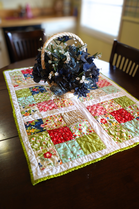 April Rosenthal orchard fabric quilted table runner fruit print patchwork 25x39 handmade - styled on a dining room table with a floral centerpiece. 